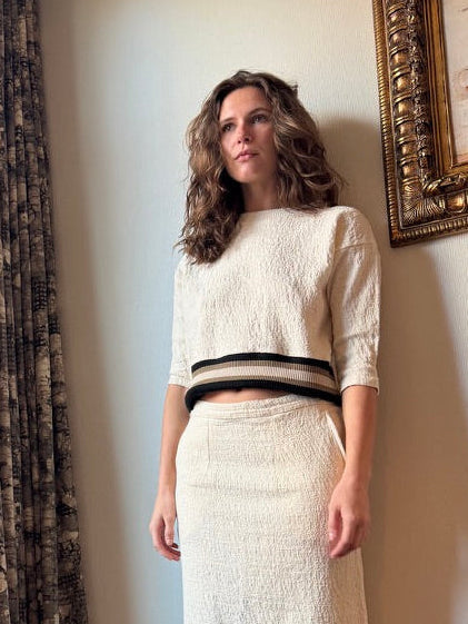 Woman standing in a room with a large window and patterned curtains